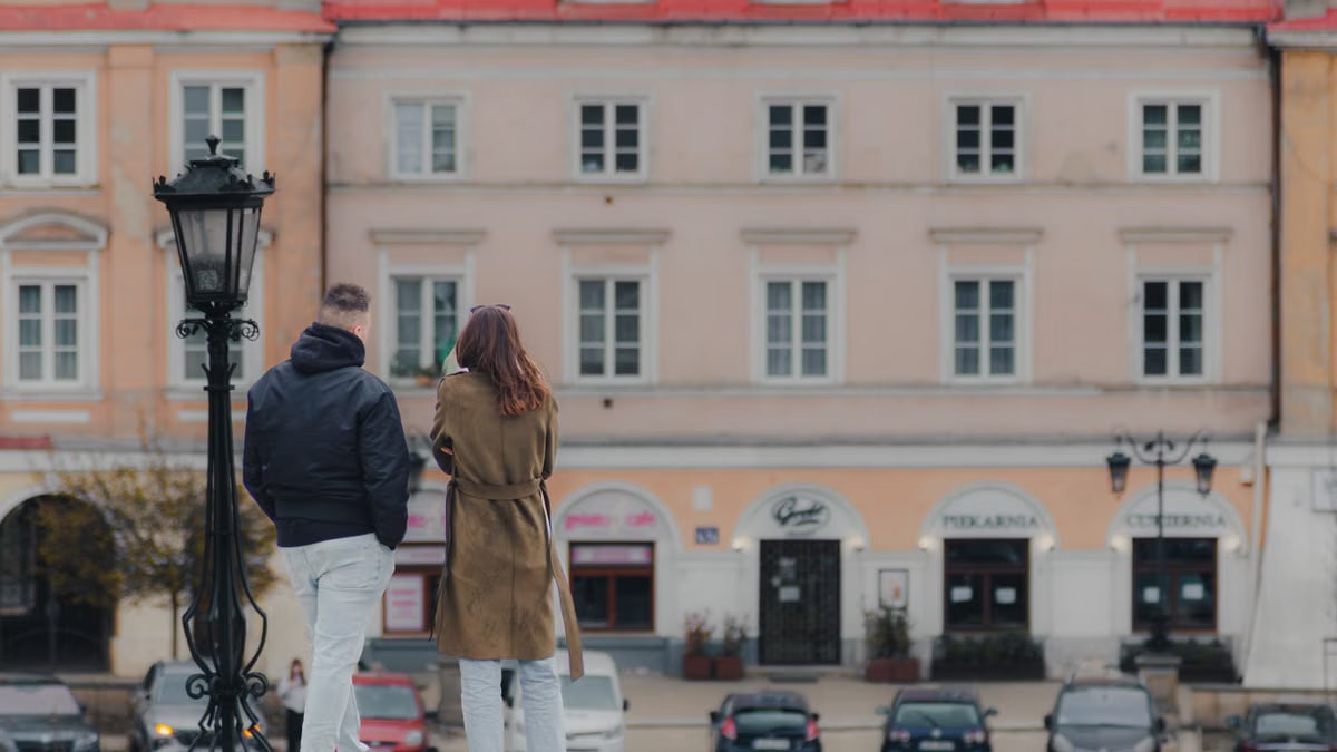 A couple stands in Lublin, Poland, enjoying the historic architecture in a city street.