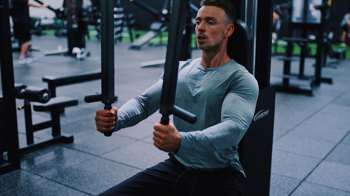 man in gray long sleeve shirt and black pants holding black metal bar